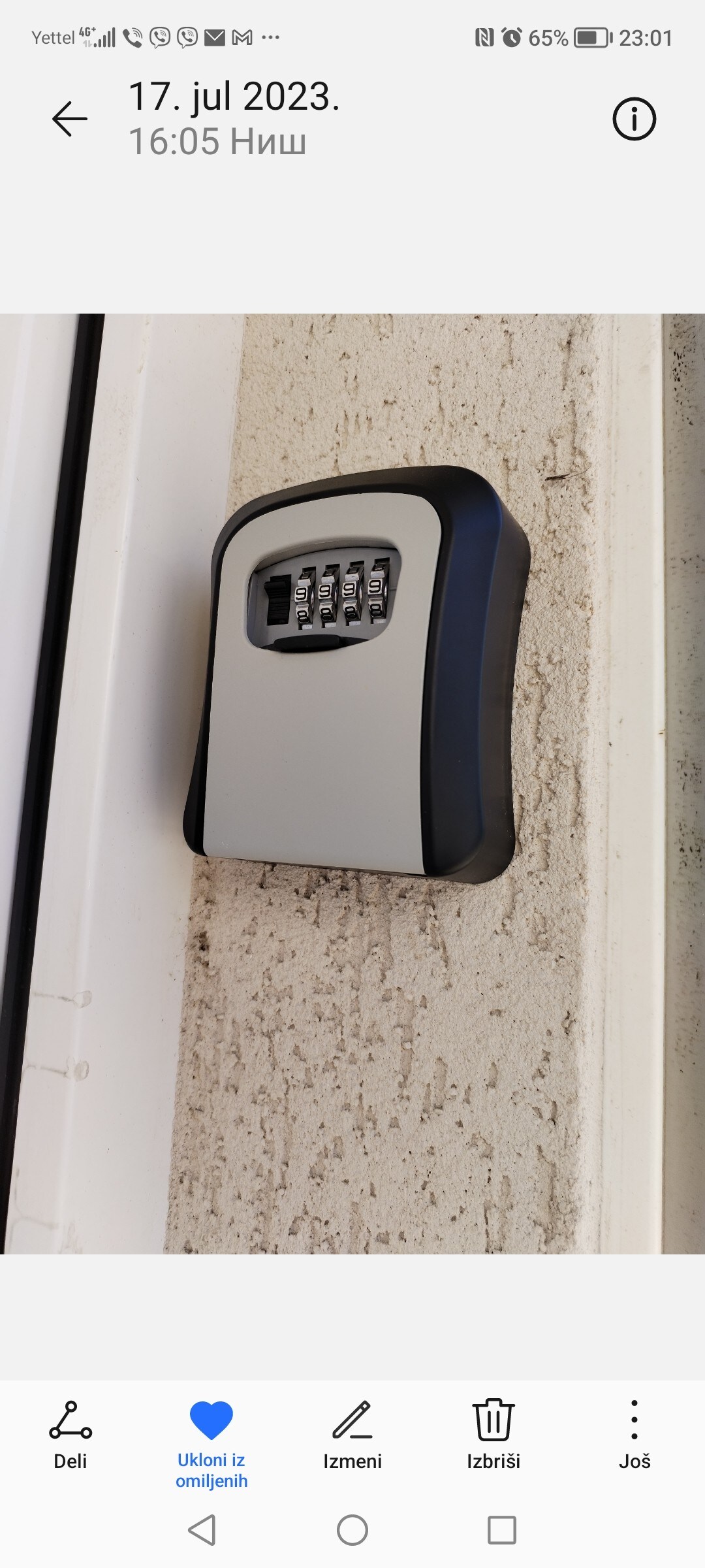 A secure key lockbox is mounted on a light-colored wall, featuring a numeric keypad. The device is positioned near the door, providing easy access for guests while ensuring safety.