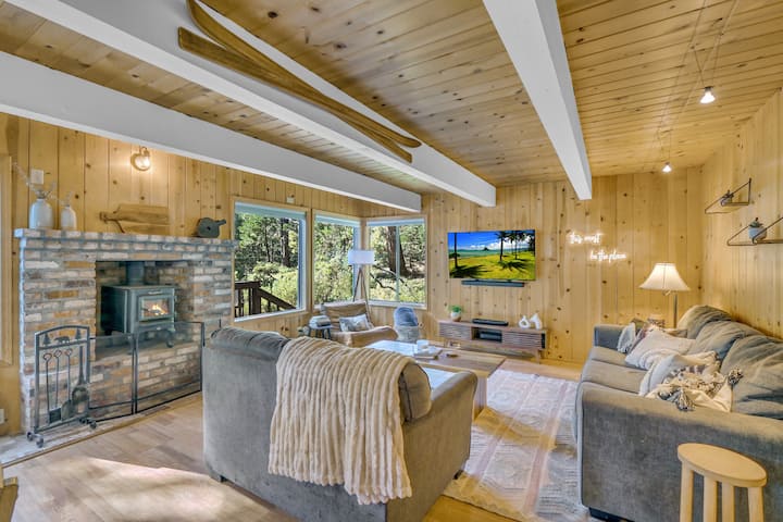 Просторна всекидневна с панорамни гледки към гората и уютна камина.