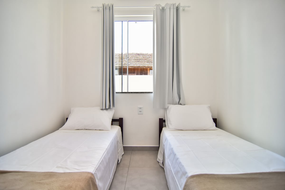 Habitación individual con colchones de 33 densidad, aire acondicionado dividido frío y caliente, ventana opaca, armario abierto con perchas.