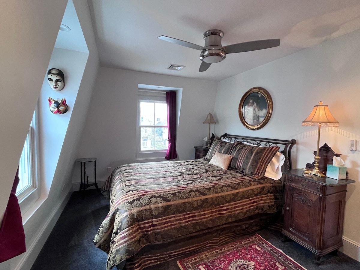 Second bedroom with queen-size wrought iron bed with antique marble-top bedside tables and Victorian-style lamps, and authentic Venetian masks