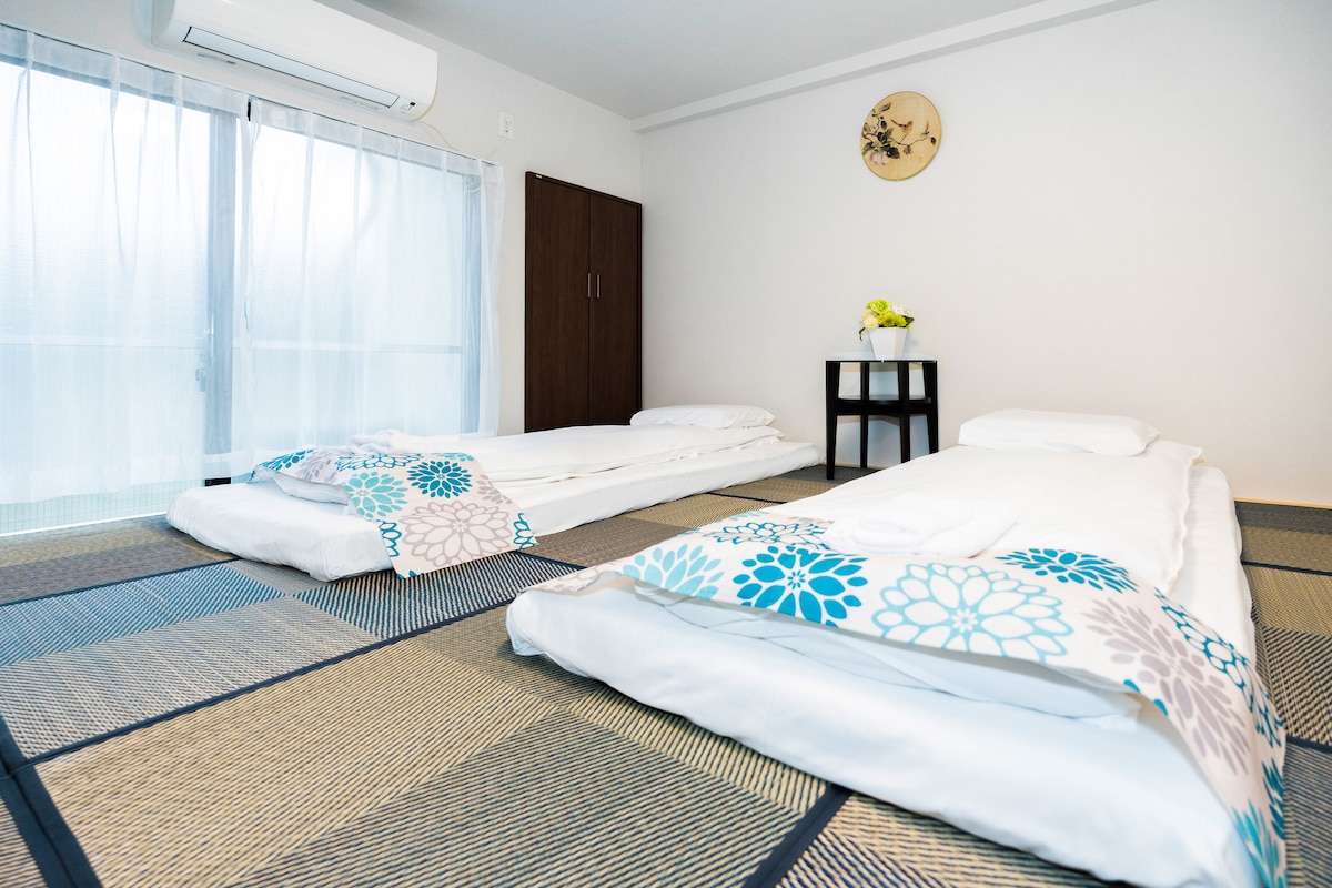 Two traditional Japanese futon beds laid out on tatami mats in a bright bedroom.