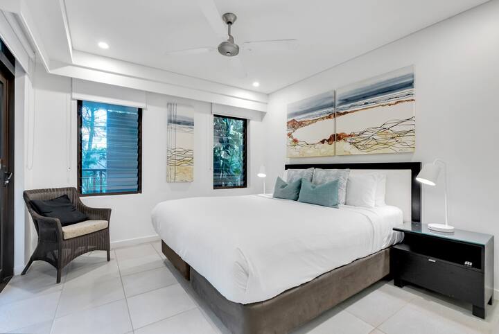 El segundo dormitorio tamaño king ofrece una esquina para sentarse, persianas y un atractivo elegante.