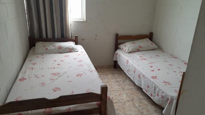 ห้องนอนพร้อมเตียงเดี่ยวสองเตียง ผ้าปูที่นอนและพัดลมเพดาน