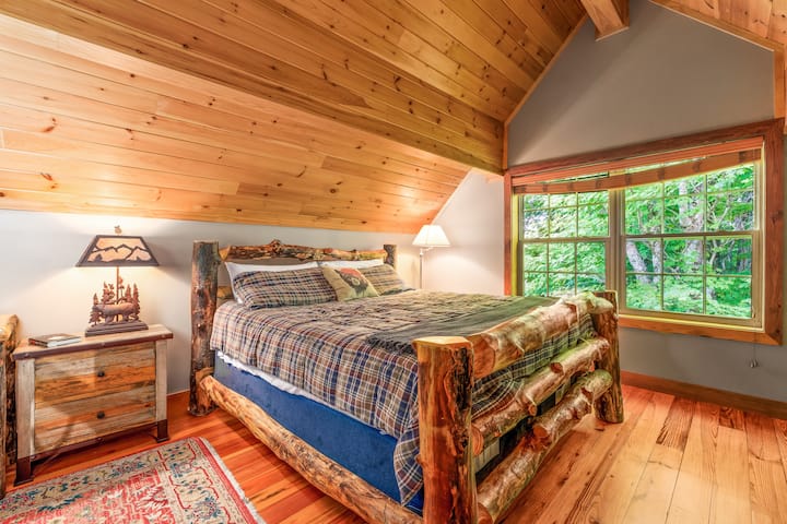 Guest bedroom with king bed, ensuite full bathroom, arched ceiling, smart TV, and relaxing mountain view.