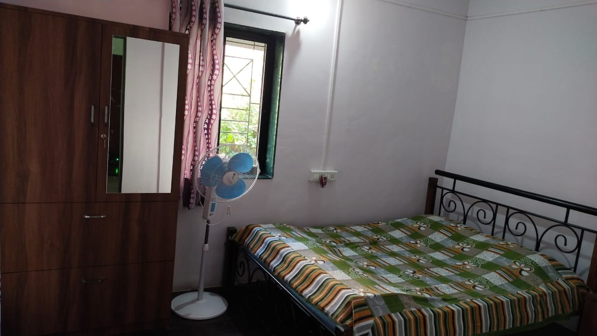 Dhomë gjumi dopio me ventilator për piedestale, gardërobë dhe dollap pranë krevatit.