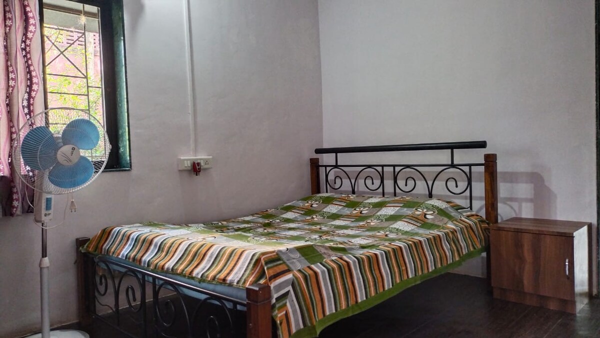 Dhomë gjumi dopio me ventilator për piedestale, gardërobë dhe dollap pranë krevatit.