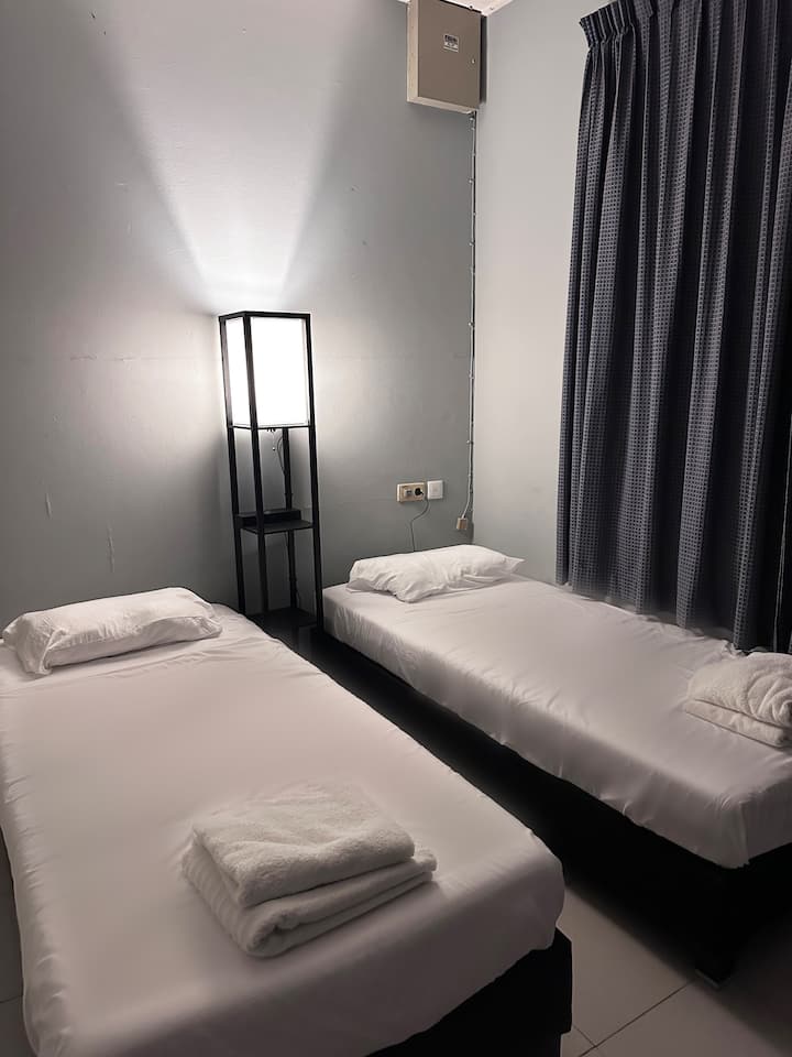 Spálňa s dvoma samostatnými posteľami, priestranná skriňa so zrkadlom a klimatizáciou pre optimálne pohodlie. Nočný stolík má lampu a bezdrôtovú nabíjaciu stanicu pre váš telefón.