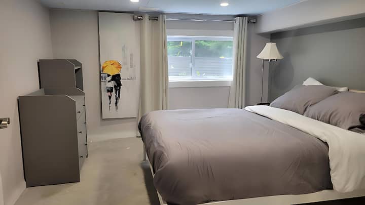 Cozy bedroom located in the basement featuring a 14-inch premium foam mattress and a dresser for clothing