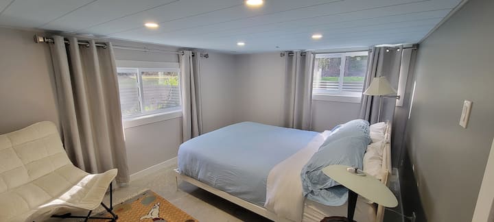 Light-filled bedroom with two large windows, with a plush 14-inch foam queen mattress, soft linen and extra blankets. Also includes dresser for clothing. Located in the basement.