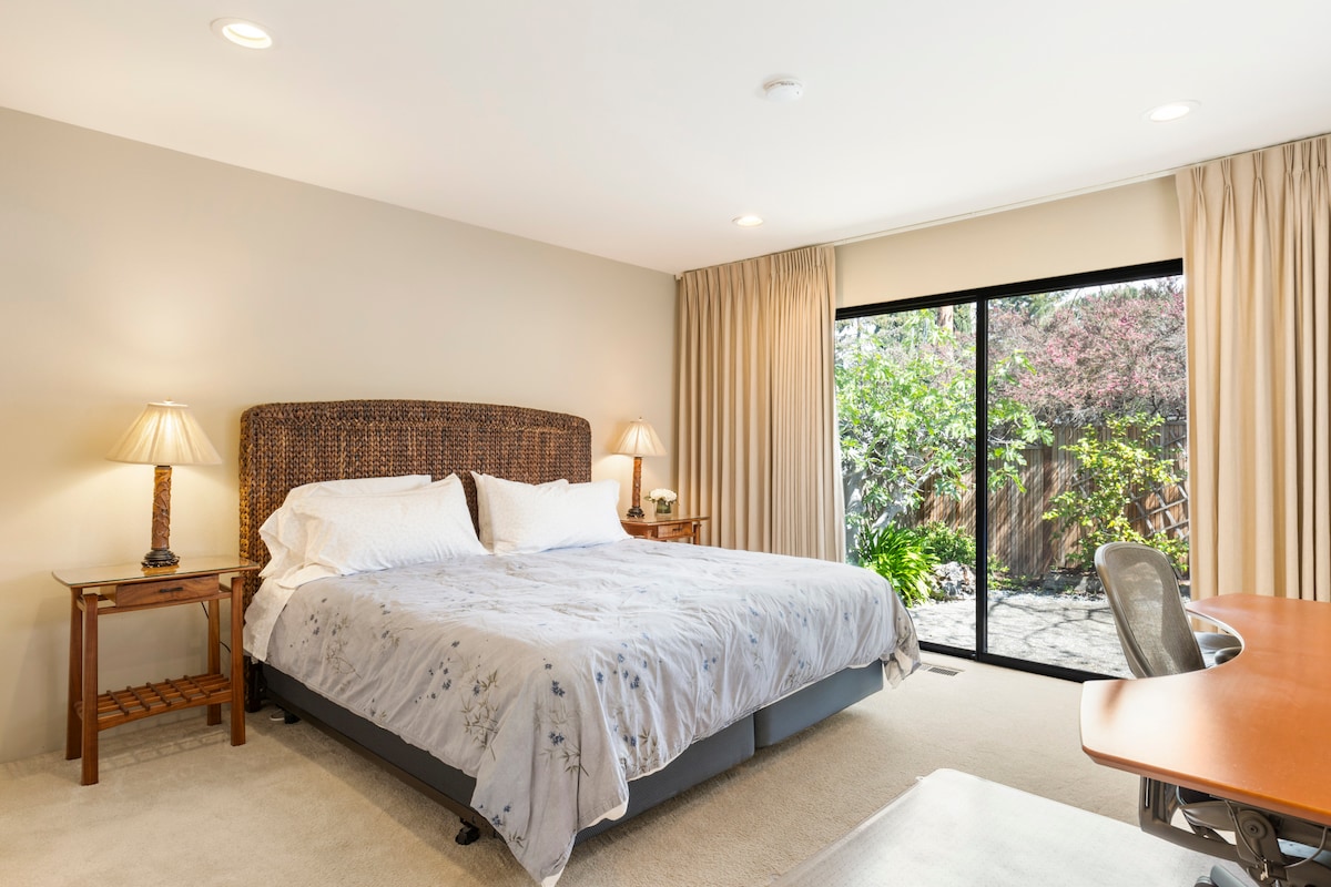 Veľká druhá spálňa s priestrannou priestrannou posteľou s výhľadom na malú záhradu vo dvore