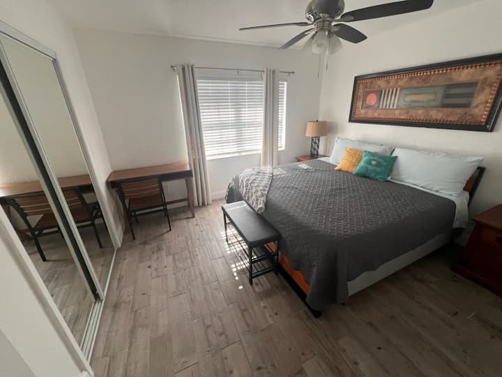 هذه هي غرفة النوم الرئيسية مع سرير بمقاس كبير وخزانة كاملة ومكتب مع كرسي.  