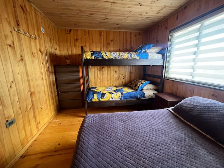 Семеен простор со дрвени детали, двоен кревет и кревет на спрат со шарена постелнина. Меката светлина создава релаксирачка средина за мирен одмор во срцето на природата. ️