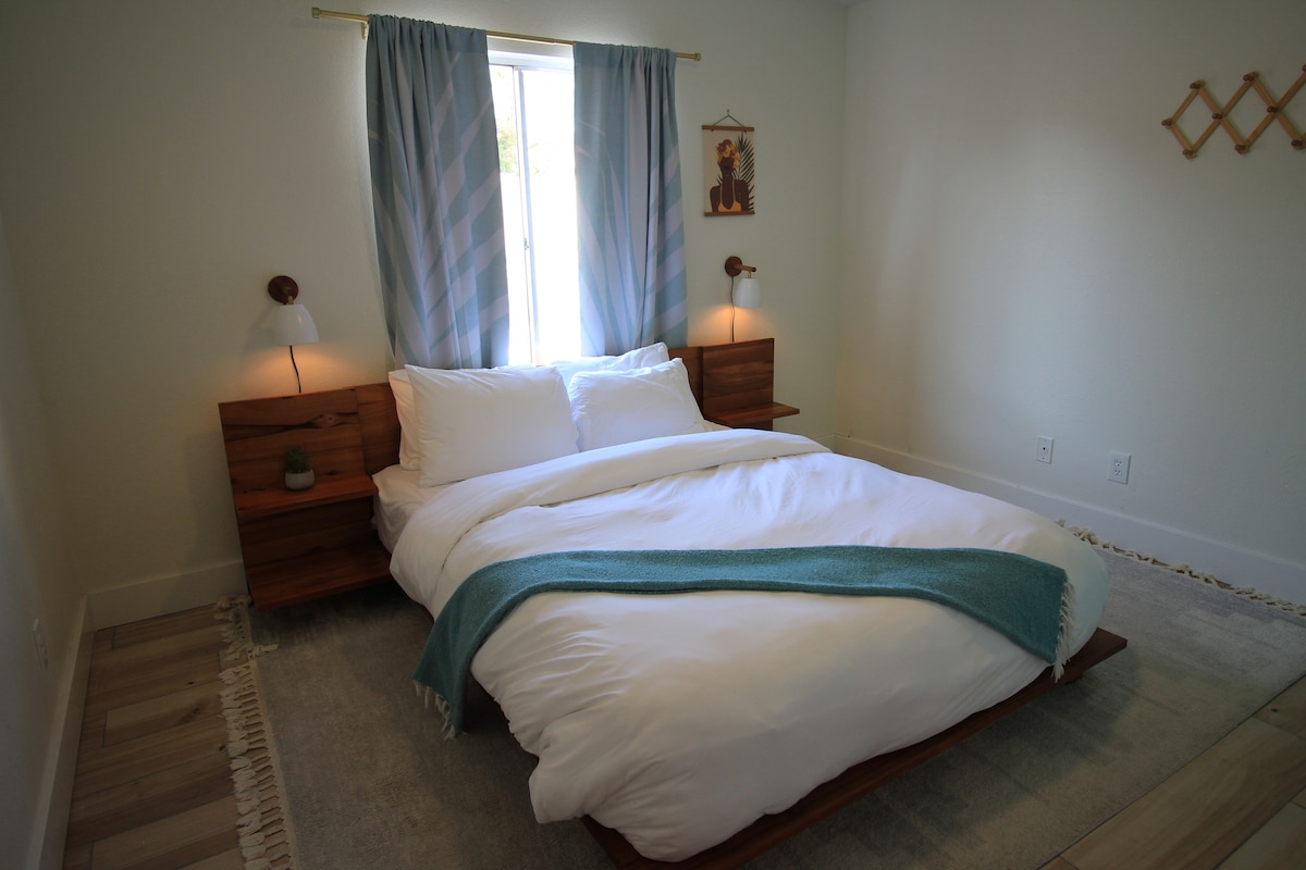 [Queen Bedroom] Queen bed with pool views, room-darkening curtains, a full-length mirror, and a closet.