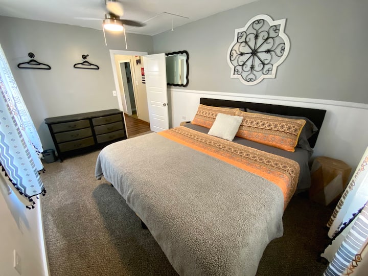 Dormitorio delantero en el primer piso con cama tamaño king, TV inteligente de 43pulgadas y persianas oscuras en la habitación.