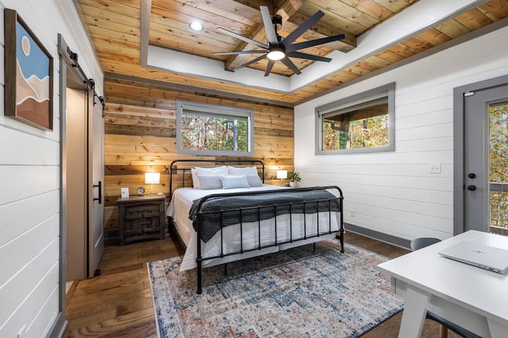 Serene primary suite with a king bed, private deck access, wooded views, and a spa-like ensuite bath. Warm wood accents blend seamlessly with modern comfort.