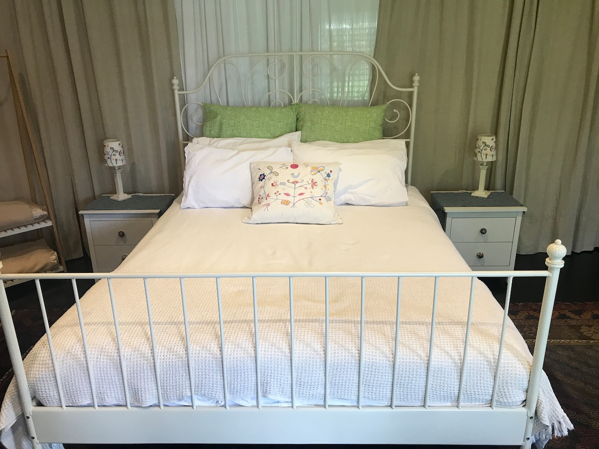 เตียงควีนไซส์สะดวกสบายพร้อมโต๊ะข้างเตียง 2 ตัวและโคมไฟ