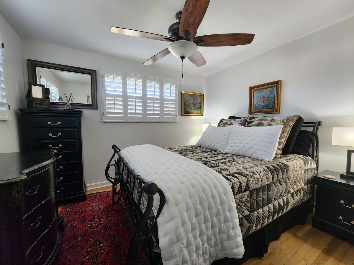 LIT QUEEN BEAUTY REST BLACK SERIES, tables de chevet, lampes, ventilateur de plafond, volets de plantation pour assombrir la chambre, armoire de salon, commode et plancher de bois franc.