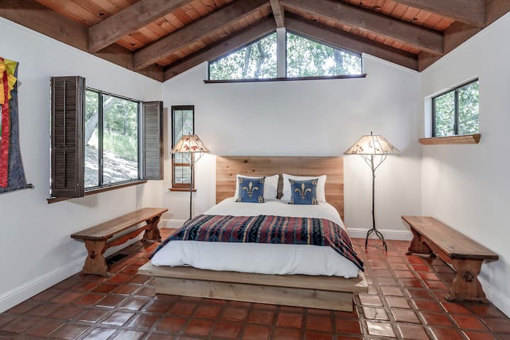 La suite principal incluye un baño. Las ventanas de la izquierda dan a un bosque de robles. Hay una barandilla lateral a lo largo de la cama para libros, teléfonos móviles y demás. 