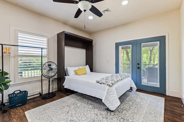 Fleksibilna soba za goste s preklopnim krevetom, stropnim ventilatorom i francuskim vratima koja vode van.