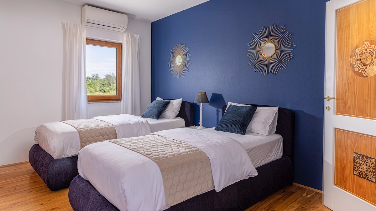 Një dhomë gjumi dyshe elegante me theks të thellë blu, ndriçim të butë dhe dekor elegant, që ofron rehati dhe bukuri. A mund ta imagjinosh të zgjohesh këtu? Prenoto qëndrimin tënd tani!