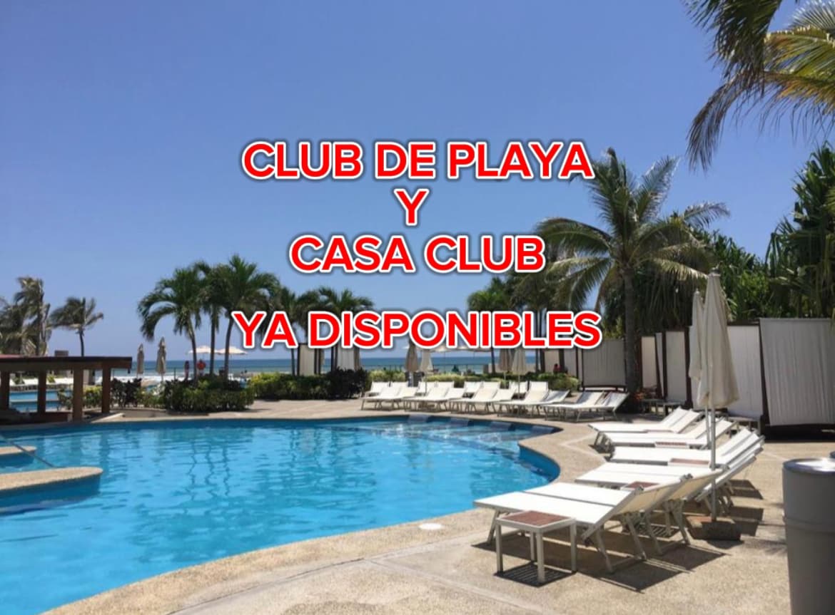 A refreshing swimming pool is surrounded by lounge chairs and palm trees, providing a resort-like atmosphere. A beach club and clubhouse are in view, offering access to additional amenities in a sunny environment.