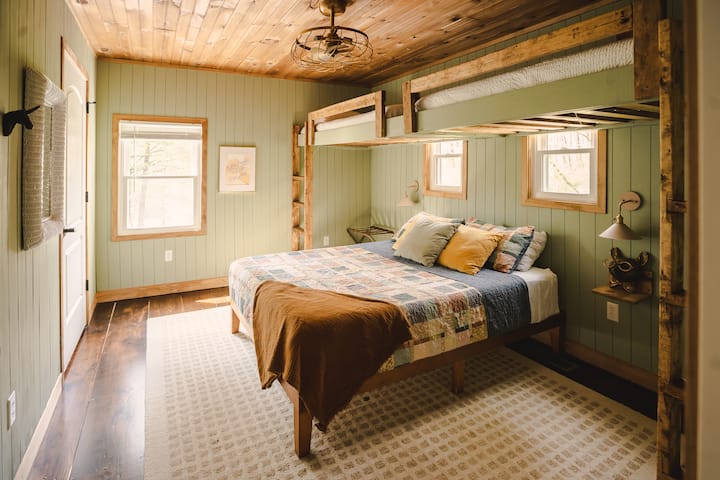 The bunk room comfortably accommodates four guests, featuring a queen bed and two twin beds for a restful night's sleep.