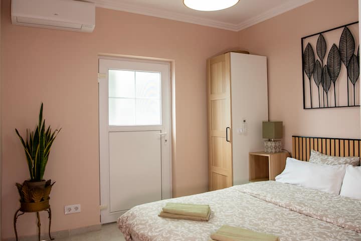 Une charmante chambre avec salle de bains privative avec douche et WC s'ouvre sur une terrasse avec table, chaises et escaliers menant à la piscine. C'est une retraite charmante pour des moments intimes et des escapades tranquilles.