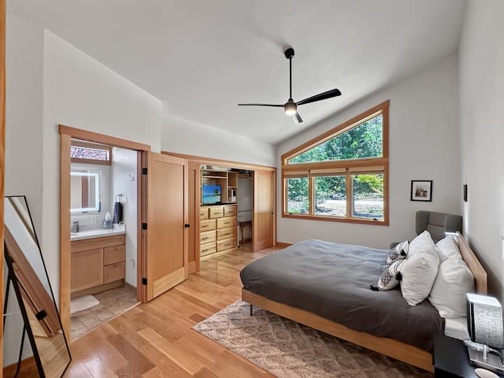 غرفة نوم رئيسية بسرير مطاطي طبيعي بحجم كبير وخزانتين كبيرتين مع خزانة ملابس وحمام متصل. يوجد تلفاز ذكي في الخزانة.