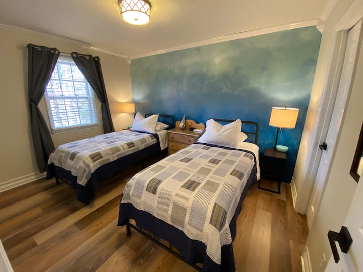 View from hallway entrance. A great timber view from this window. Each bed has its own light and charging ports table. Table top fan, more pillows, extra blankets, luggage racks, hangers, and laundry basket are in the closet for you.