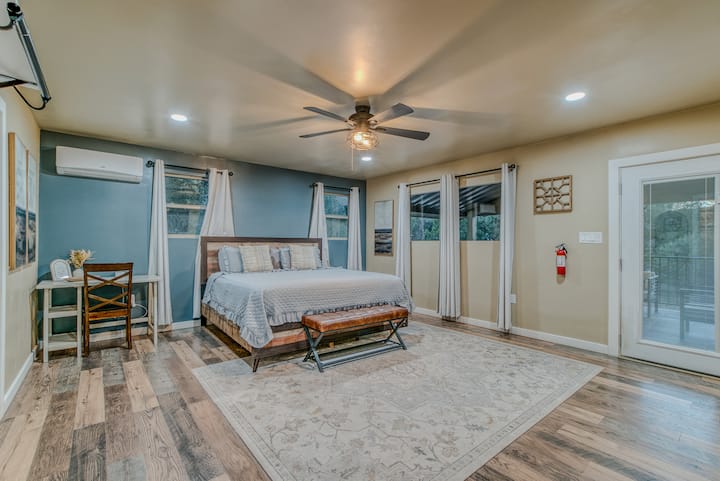 Ელეგანტური ძირითადი აპარტამენტი – მშვიდი საძინებელი დიდი ზომის საწოლით, რბილი განათებით და ღია ცის ქვეშ გასასვლელით.