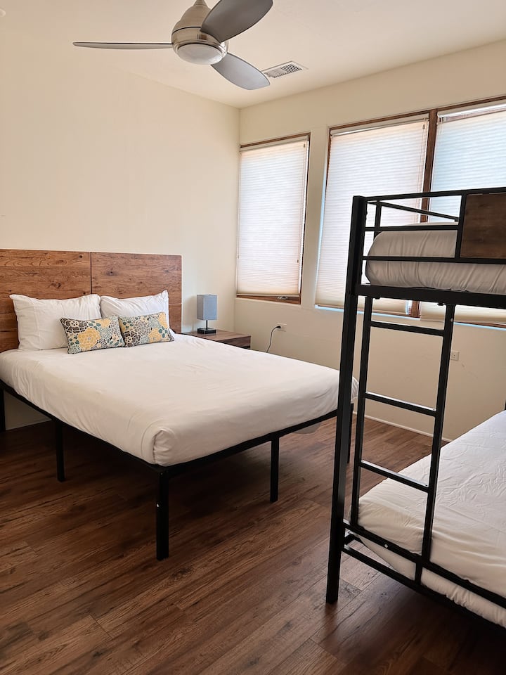 This bedroom features a cozy queen-size bed alongside a twin bunk bed—perfect for families or groups. While there’s no closet, the room is equipped with convenient luggage racks for your storage needs.