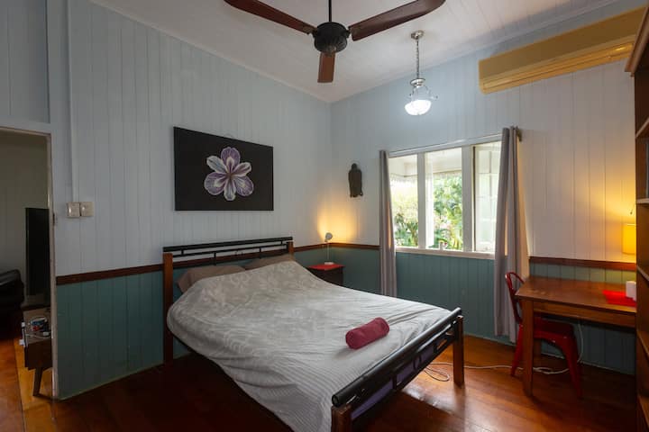 Veľká spálňa s manželskou posteľou a klimatizáciou, leštenými drevenými podlahami s výhľadom na svieže záhrady.