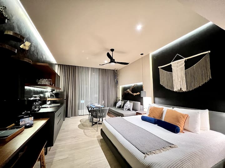 Sehemu ya kuishi yenye starehe yenye sofa kubwa, dawati lenye benchi la mbao na feni ya dari.