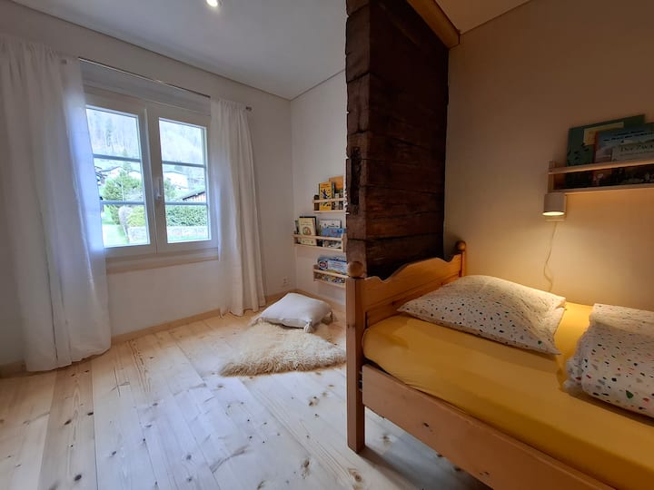 Kinderzimmer mit 2 Betten 80x190, auf Wunsch Reisebett und/oder Kinderbett vorhanden. Leseecke mit vielen Büchern. Verdunkelung mit Fensterlanden möglich. 