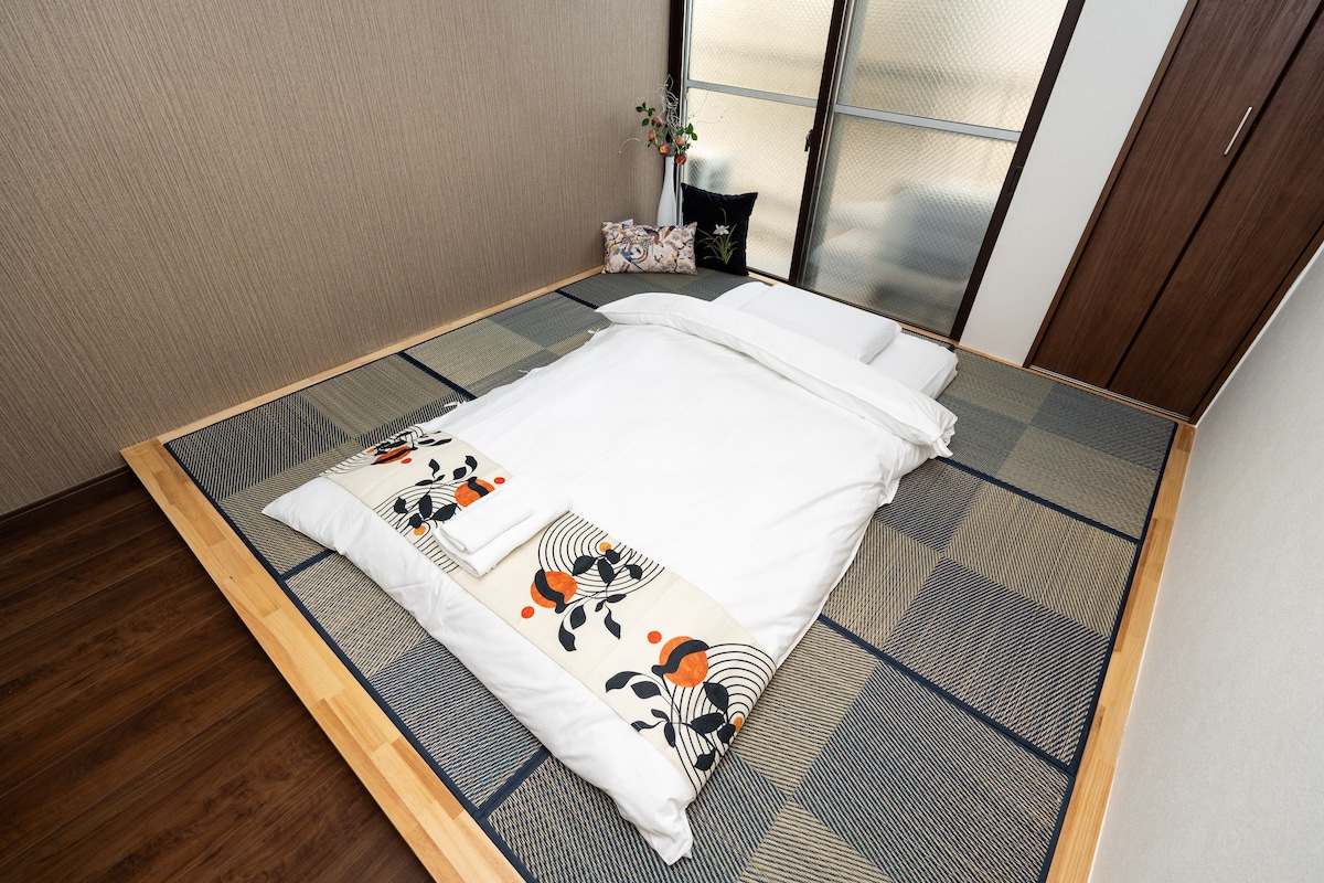 Traditional Japanese futon with white bedding laid on tatami mats in a bedroom.