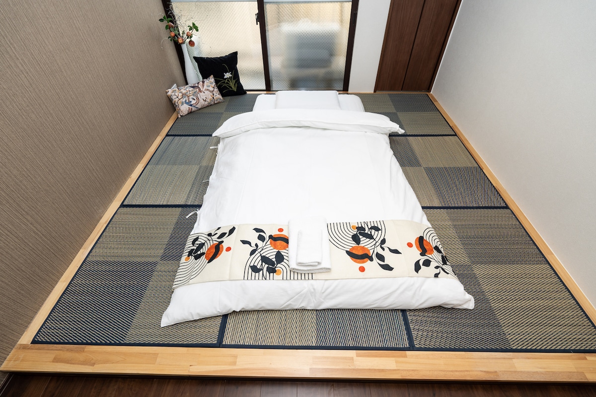 Traditional Japanese futon bed laid out on tatami mats in a minimalist bedroom.