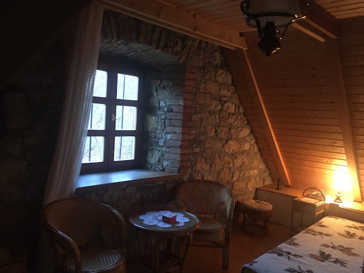 Малата соба на поткровјето има лизгачки прозорец со дебели, необработени камени ѕидови.