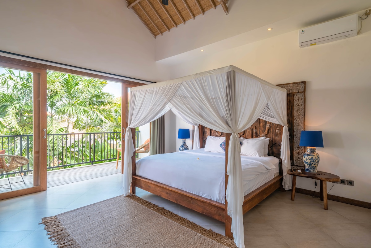 Spavaća soba s balkonom s plavim detaljima i složenim drvenim rezbarijama straga.