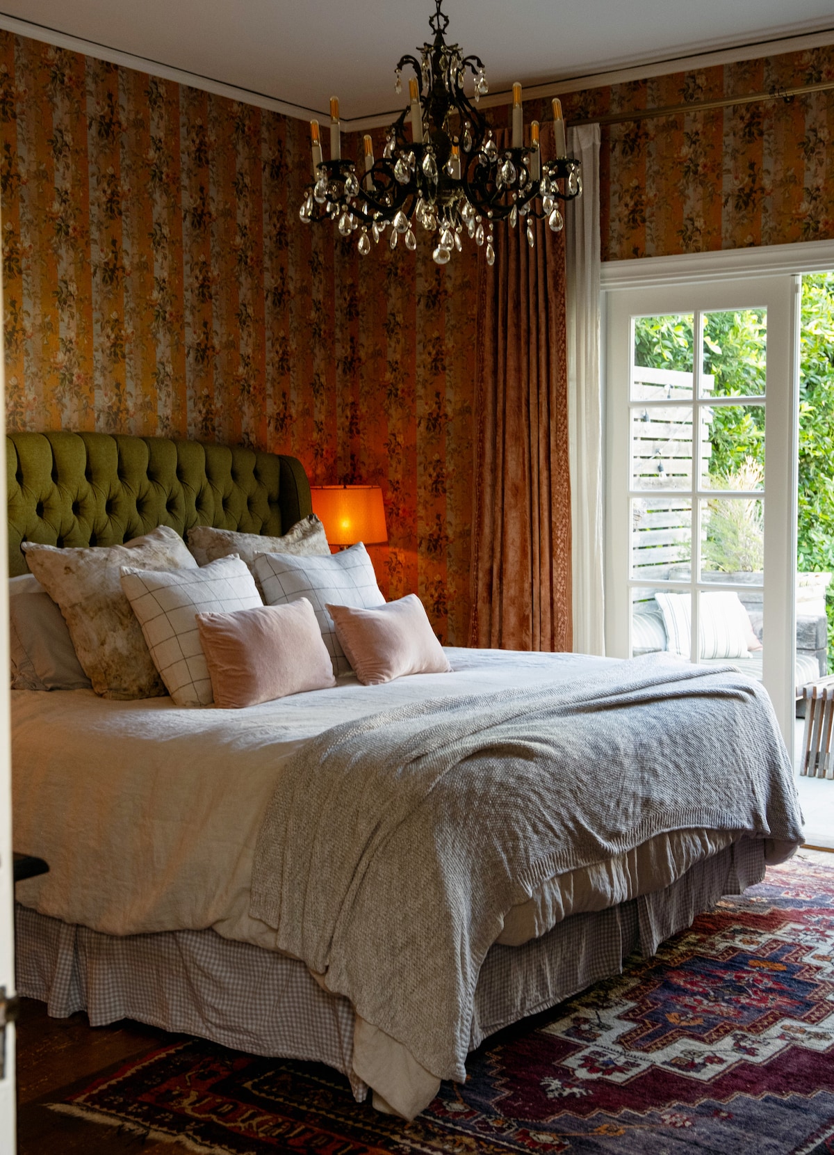 ห้องนอนหลักพร้อมเตียงคิงไซส์ ประตูสไตล์ฝรั่งเศสเปิดออกสู่ลานหินสีฟ้าและสนามหลังบ้าน 