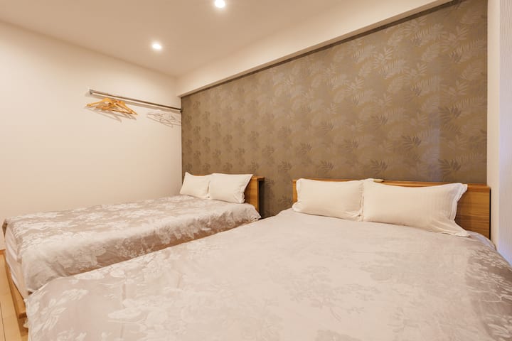 El dormitorio 3 tiene dos camas grandes de aproximadamente 1,5 metros de ancho, que pueden alojar hasta cuatro adultos, por lo que es una opción ideal para familias y amigos que viajan juntos.El colchón es suave y cómodo, con ropa de cama limpia y agradable para la piel para que tengas un sueño tranquilo.La habitación está equipada con aire acondicionado para garantizar una temperatura agradable tanto en verano como en invierno.Además, también hay perchas bien pensadas para que el viaje sea más cómodo y ordenado.Hay una distancia moderada entre las camas, lo que mejora la independencia y la facilidad de uso.El espacio general está bien iluminado, con tonos suaves en paredes y suelos, lo que crea un ambiente luminoso, ordenado y acogedor.
