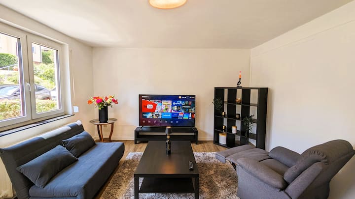 宽敞的光线充足的客厅，配有沙发床、豪华电视扶手椅和智能电视。 