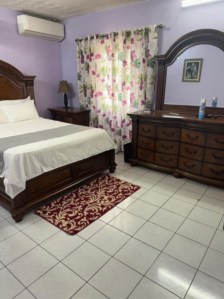 Cette chambre principale est climatisée et dispose également d'un ventilateur mural et d'une télévision.