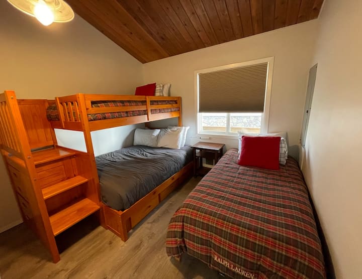 غرفة نوم للأطفال بسريرين مزدوجين وسرير كامل الحجم.