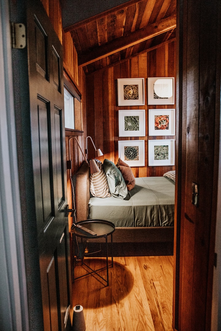 Bedroom 2 provides a luxurious organic Saatva mattress, overlooking the majestic redwoods. It also offers a convenient workspace for any necessary tasks, complete with bedside chargers and outlets for easy charging.
