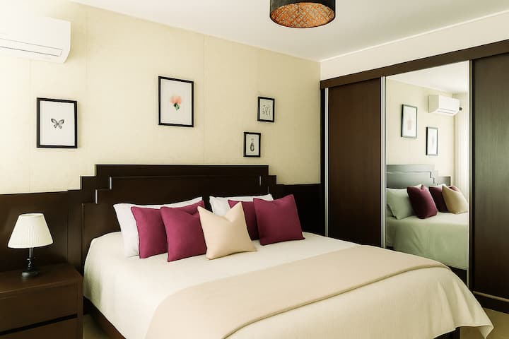 Rest in a cozy room with a king size bed, elegant headboard and spacious closet with mirror. Enjoy natural light, air conditioning or heating, as well as modern decor that invites relaxation and comfort