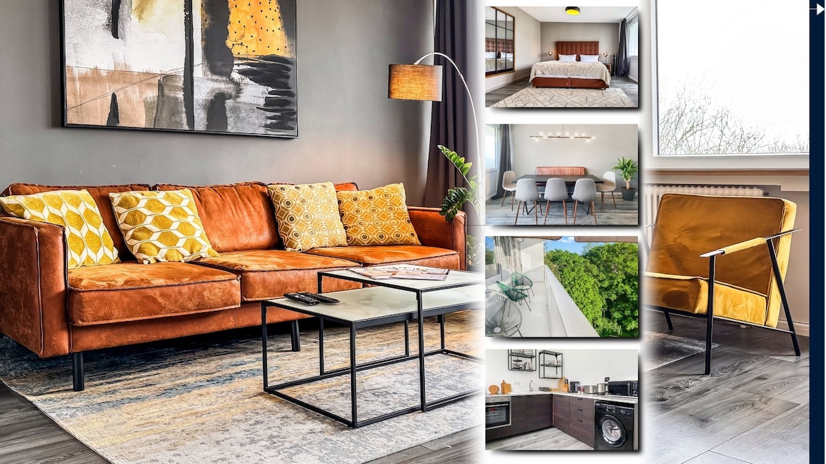 A welcoming living area features a warm brown leather sofa with vibrant yellow accent pillows. A contemporary abstract painting adorns the wall above, while a sleek coffee table sits on a textured grey rug. Natural light filters in through large windows, enhancing the space.