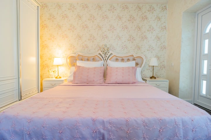 This serene bedroom offers a peaceful retreat with its soft pastel color palette, a comfortable double bed with plush bedding, and ample storage in the built-in wardrobes for a relaxing stay.