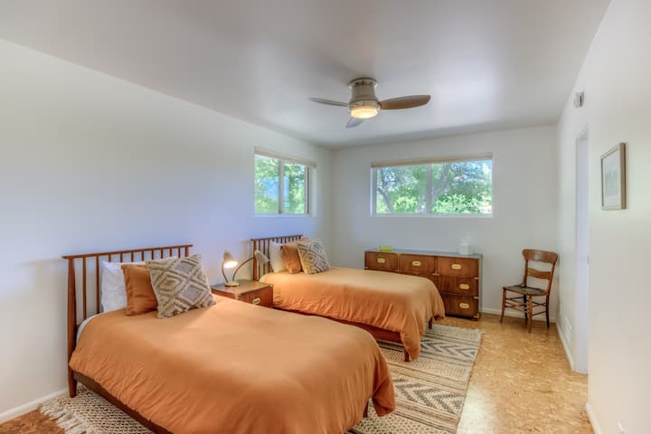 Bedroom with two twin beds, closet with kids toys and books, dresser, ceiling fan and ensuite bathroom with shower and single vanity.