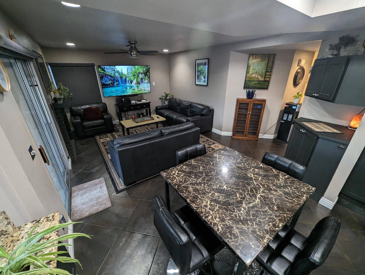 Sala de estar y 4 taburetes mesa de comedor frente al televisor con barra de sonido. 4 altavoces en el techo Sonos Music.  Mountain Valley Spring Water en una botella de vidrio, enfriador/calentador de agua autolimpiante. Phillips Hue Ilumina 16 millones de colores en todo el alojamiento.