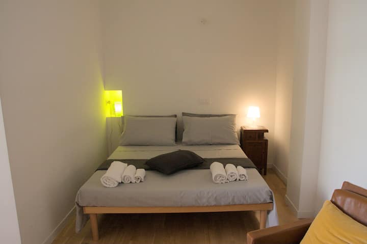 Un lit double confortable avec des draps et des serviettes propres dans la zone nuit de l'appartement